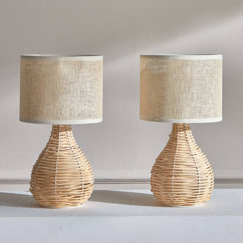 Two wicker table lamps with beige lampshades on a light surface.