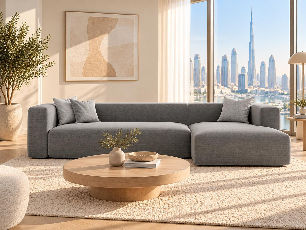 Grey L-shaped linen sectional sofa in a bright Dubai apartment living room with skyline view