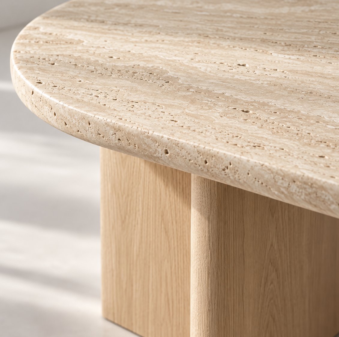 Close-up of the rounded travertine edge and oak leg of the Sola dining table